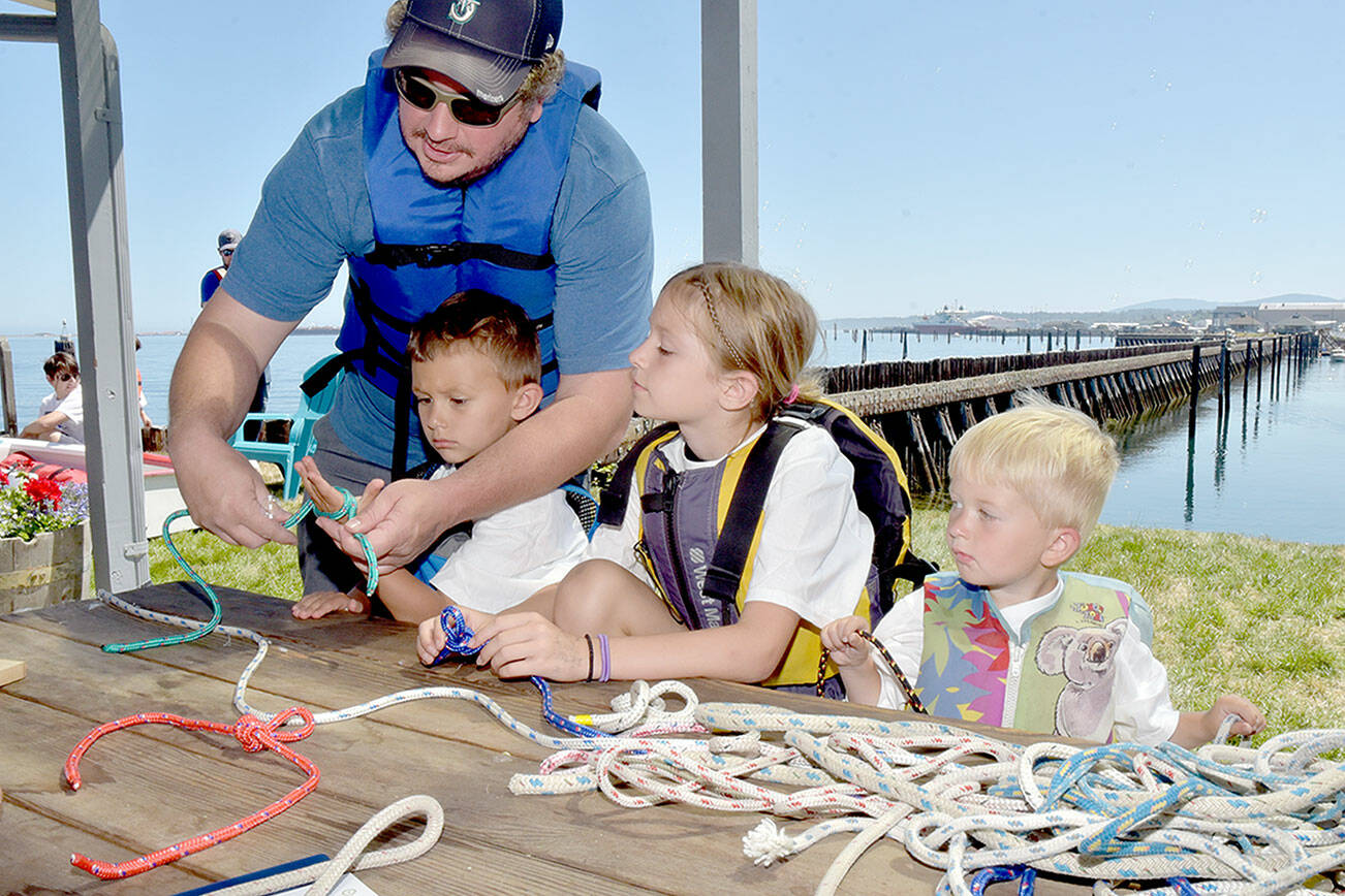 Brian Hoffman of Port Angeles, left, assists his children, from left, Clayton Hoffman, 6, Lacey Hoffman, 8, and Rhett Hoffman, 3, during a knot-tying workshop at the Port Angeles Yacht Club, one of numerous venues for Saturday’s Day of Play. (Keith Thorpe/Peninsula Daily News)