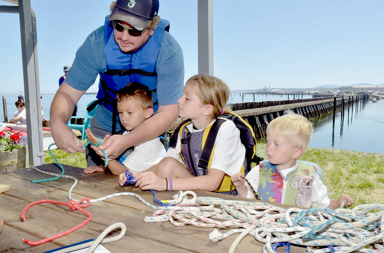 Brian Hoffman of Port Angeles, left, assists his children, from left, Clayton Hoffman, 6, Lacey Hoffman, 8, and Rhett Hoffman, 3, during a knot-tying workshop at the Port Angeles Yacht Club, one of numerous venues for Saturday’s Day of Play. (Keith Thorpe/Peninsula Daily News)