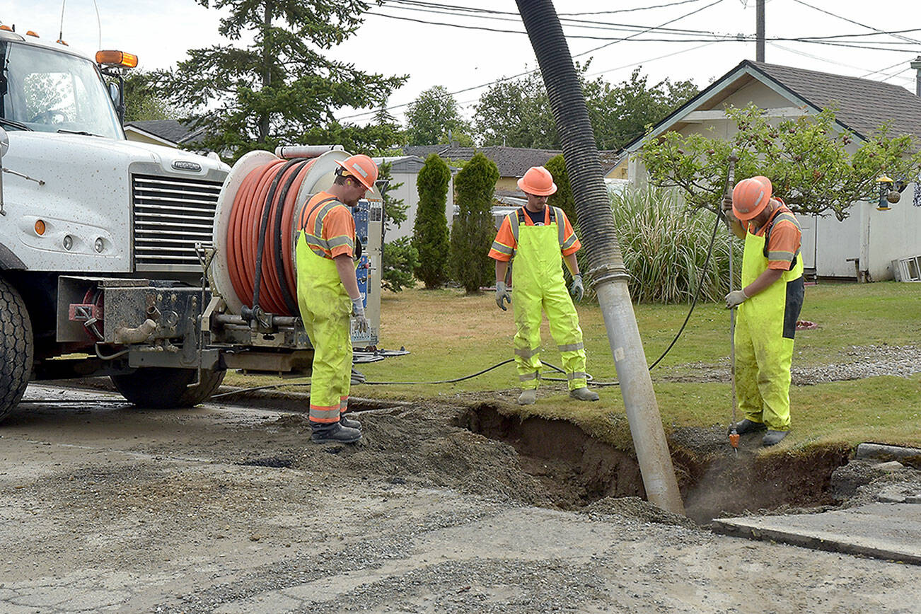 A Port Angeles public utilities crew vacuums out water and debris from a hole around a water main break on South H Street near West Sixth Street on Wednesday morning. (Keith Thorpe/Peninsula Daily News)