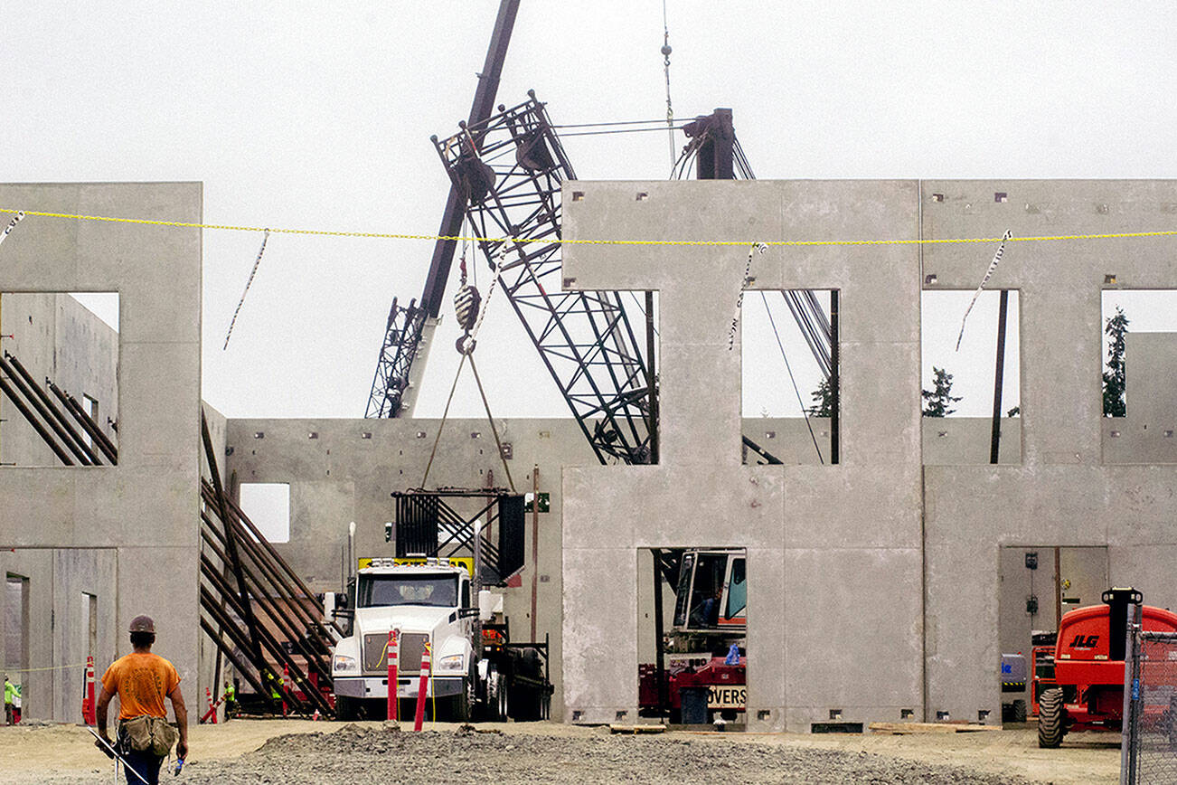 Abbot Construction’s crew responsible for crane lifting the two-story concrete walls pack up as new crew members move in for steel reinforcement on Monday. (Elijah Sussman/Peninsula Daily News)