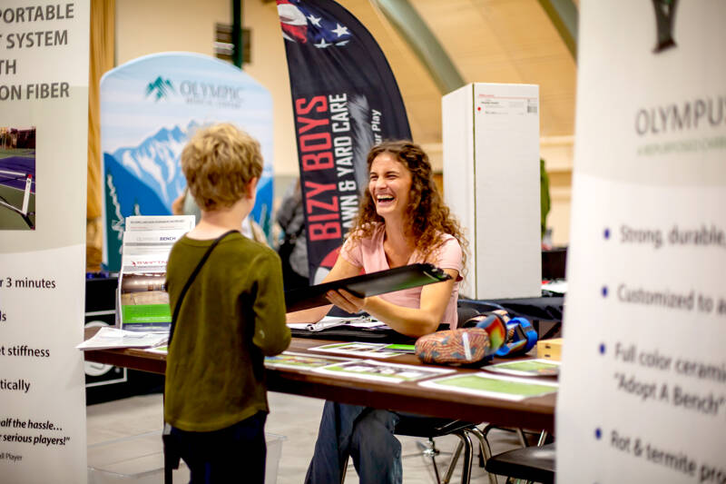 Maya DeLano, executive assistant at Composite Recycling Technology Center, demonstrates the durability of recycled carbon fiber during a job fair on Friday organized by the Port Angeles Chamber of Commerce at the Vern Burton Community Center. (Christopher Urquia/Peninsula Daily News)