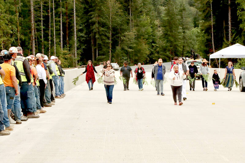 Lower Elwha Klallam Tribal Chairwoman Francis Charles leads tribal members in a ceremony across the length of the new Elwha River bridge, which opened Sunday afternoon. The tribal members dedicated the surface with cedar bows as members of the bridge crew watched from left. (Dave Logan/for Peninsula Daily News)