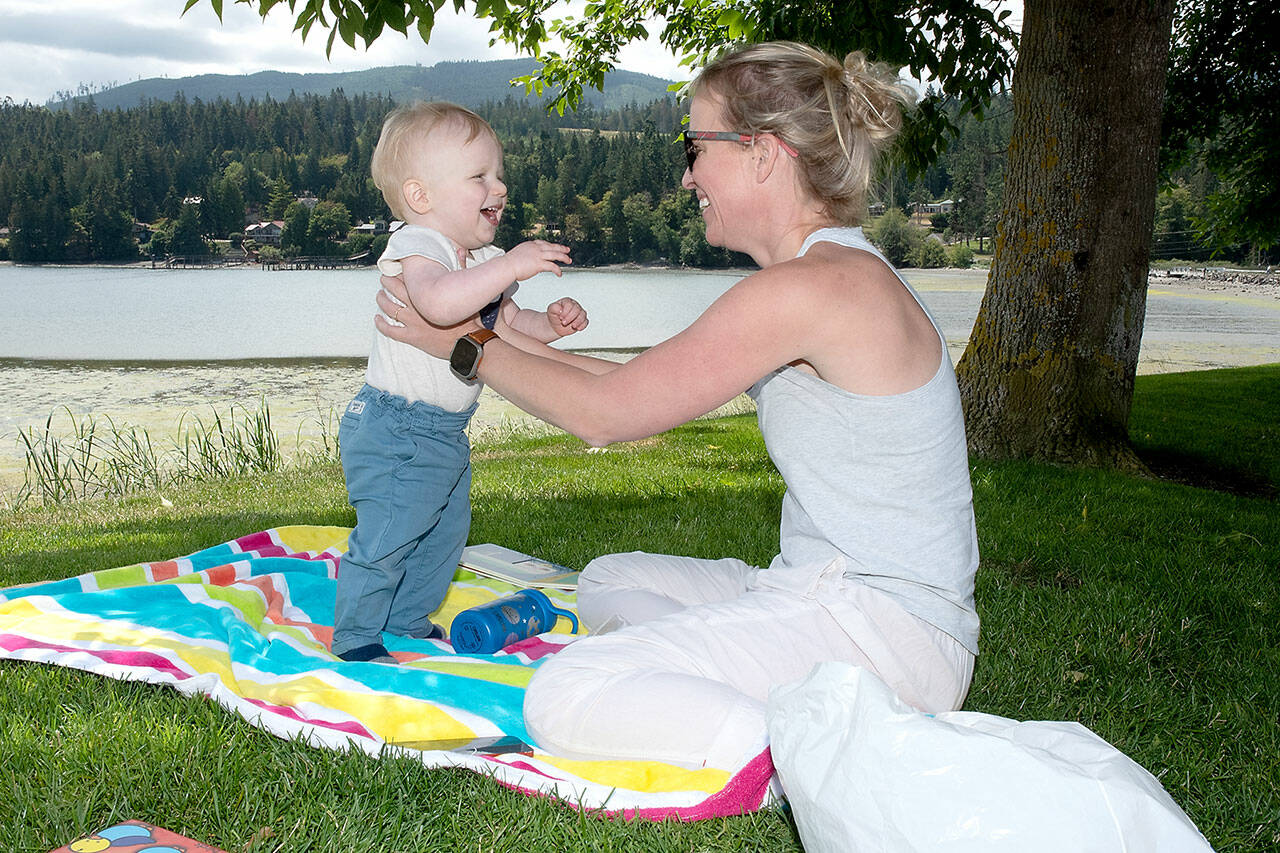 Jamie Nautsch of Sequim plays with her son Christian Nautsch, 1, on the lawn overlooking Sequim Bay at John Wayne Marina on Thursday. Summer-like weather made for a pleasant day next to the water. (KEITH THORPE/PENINSULA DAILY NEWS)