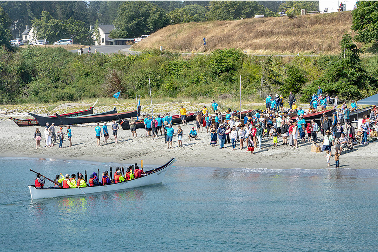 A canoe from the Scianew Tribe, from Beecher Bay on Vancouver Island, approaches the beach and asks permission to land from a Jamestown S’Klallam tribal member on the beach. The annual Intertribal Canoe Journey, this year also known as the Power Paddle to Puyallup Youth Canoe Journey, landed 13 canoes from around the Olympic Peninsula and Canada on the beach at Fort Worden on Friday. The Jamestown S’Klallam Tribe is the host tribe for the landings in Port Townsend. (Steve Mullensky/for Peninsula Daily News)