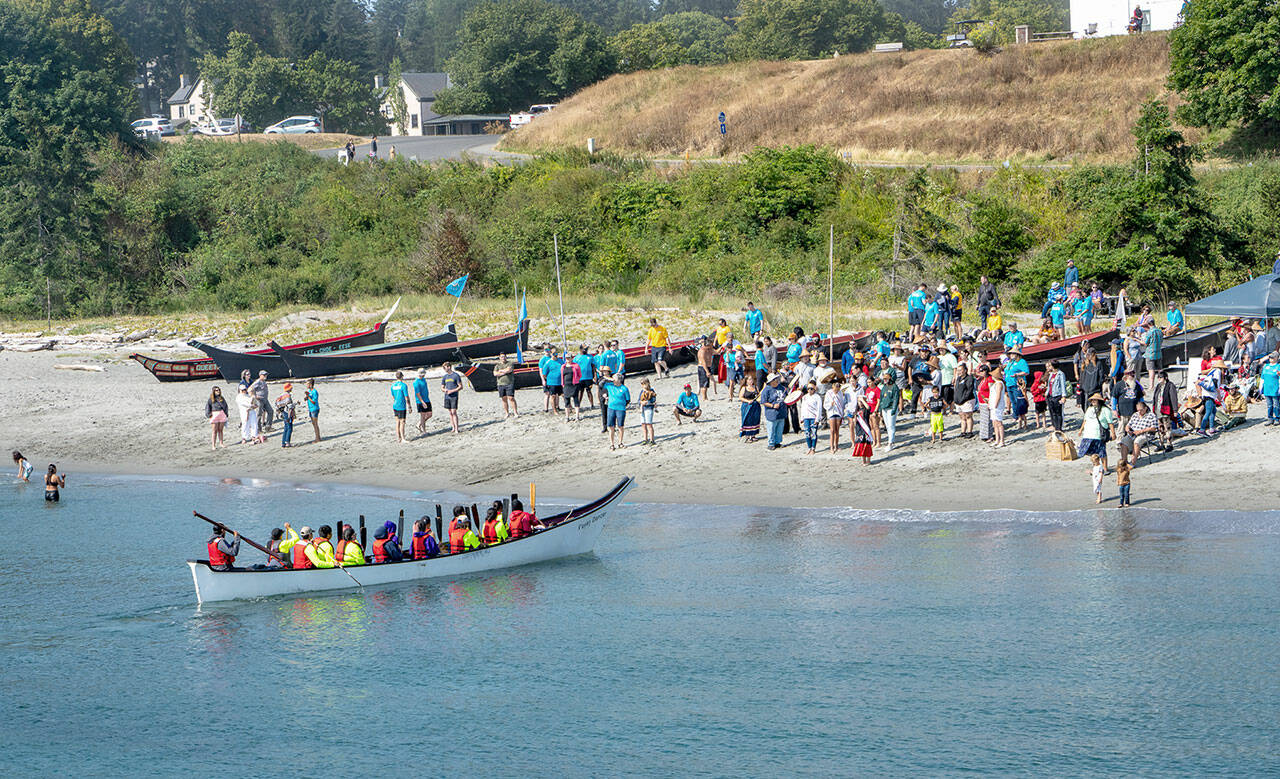 A canoe from the Scianew Tribe, from Beecher Bay on Vancouver Island, approaches the beach and asks permission to land from a Jamestown S’Klallam tribal member on the beach. The annual Intertribal Canoe Journey, this year also known as the Power Paddle to Puyallup Youth Canoe Journey, landed 13 canoes from around the Olympic Peninsula and Canada on the beach at Fort Worden on Friday. The Jamestown S’Klallam Tribe is the host tribe for the landings in Port Townsend. (Steve Mullensky/for Peninsula Daily News)