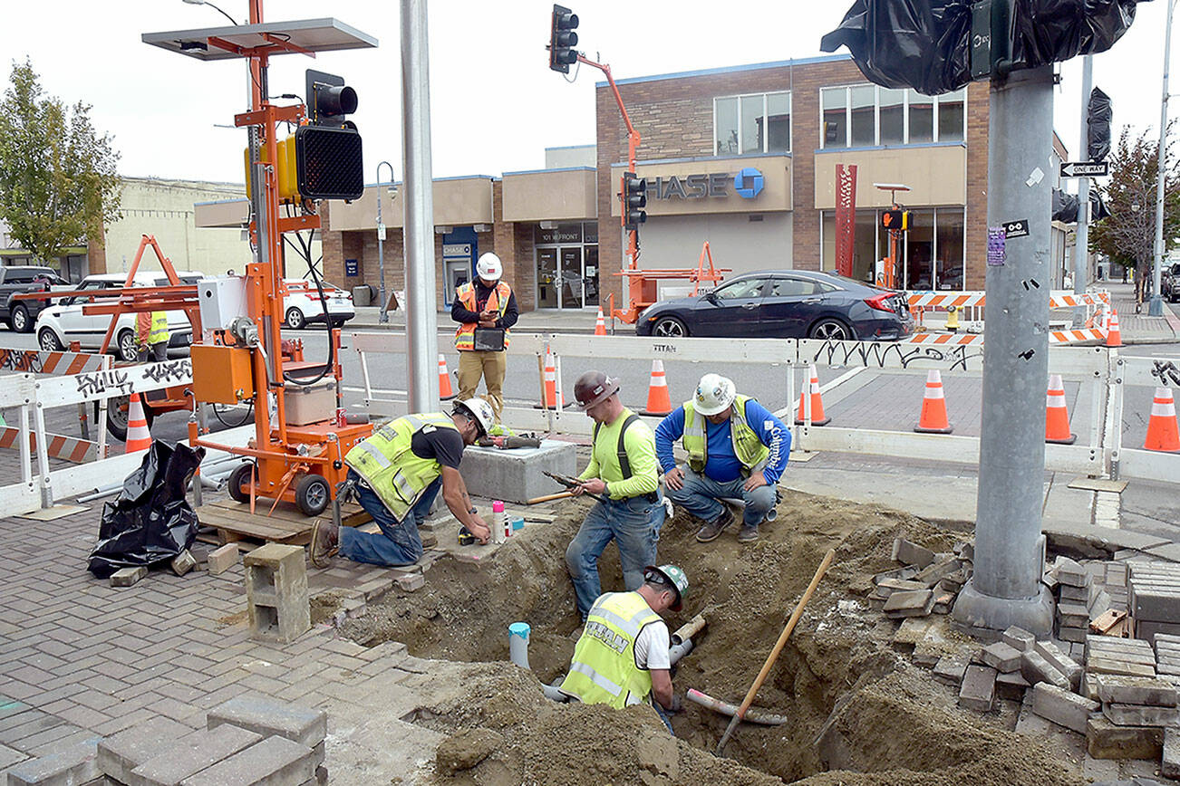 A crew from Pacific-based Titan Earthwork LLC rewires the traffic lights at Front and Laurel streets in downtown Port Angeles on Tuesday as part of a larger safety project to improve 13 intersections across the city. Plans call for replacing signal timing equipment and inclusion of ADA-compliant curb ramps as well as sidewalk repairs around work sites. The $5.6 million project is expected to be completed by December. (Keith Thorpe/Peninsula Daily News)