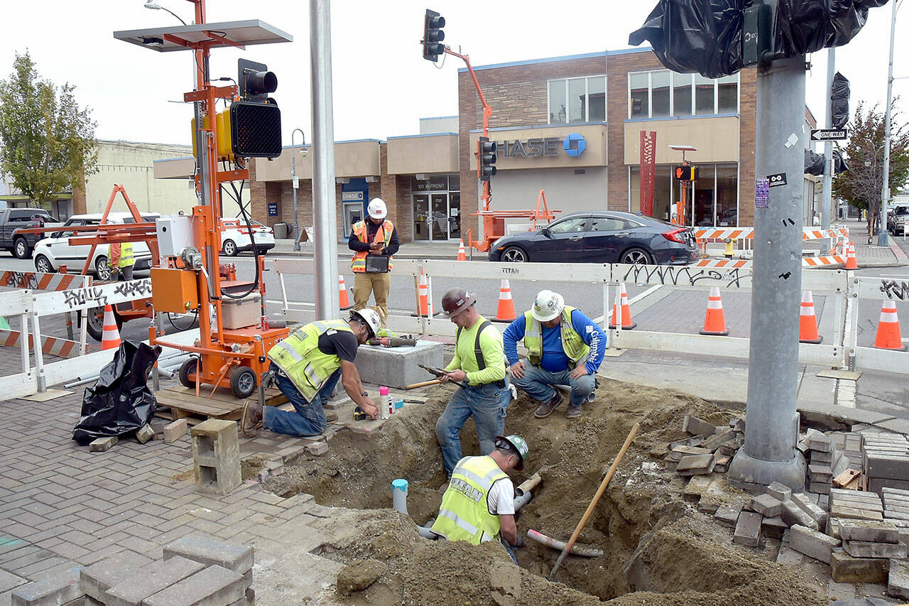 A crew from Pacific-based Titan Earthwork LLC rewires the traffic lights at Front and Laurel streets in downtown Port Angeles on Tuesday as part of a larger safety project to improve 13 intersections across the city. Plans call for replacing signal timing equipment and inclusion of ADA-compliant curb ramps as well as sidewalk repairs around work sites. The $5.6 million project is expected to be completed by December. (Keith Thorpe/Peninsula Daily News)