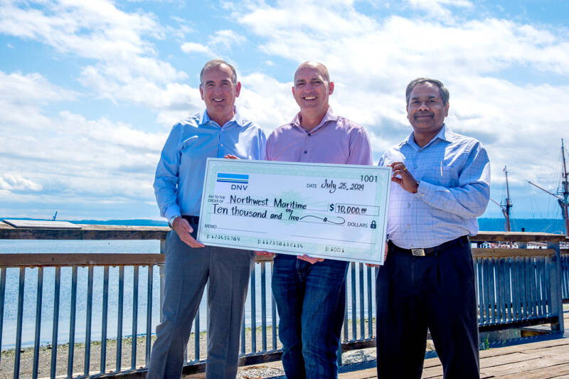From left, Gregg Madden, Jake Beattie and Gopal Nair hold a check donation from DNV to Northwest Maritime at the Northwest Maritime campus in Port Townsend. (Northwest Maritime)