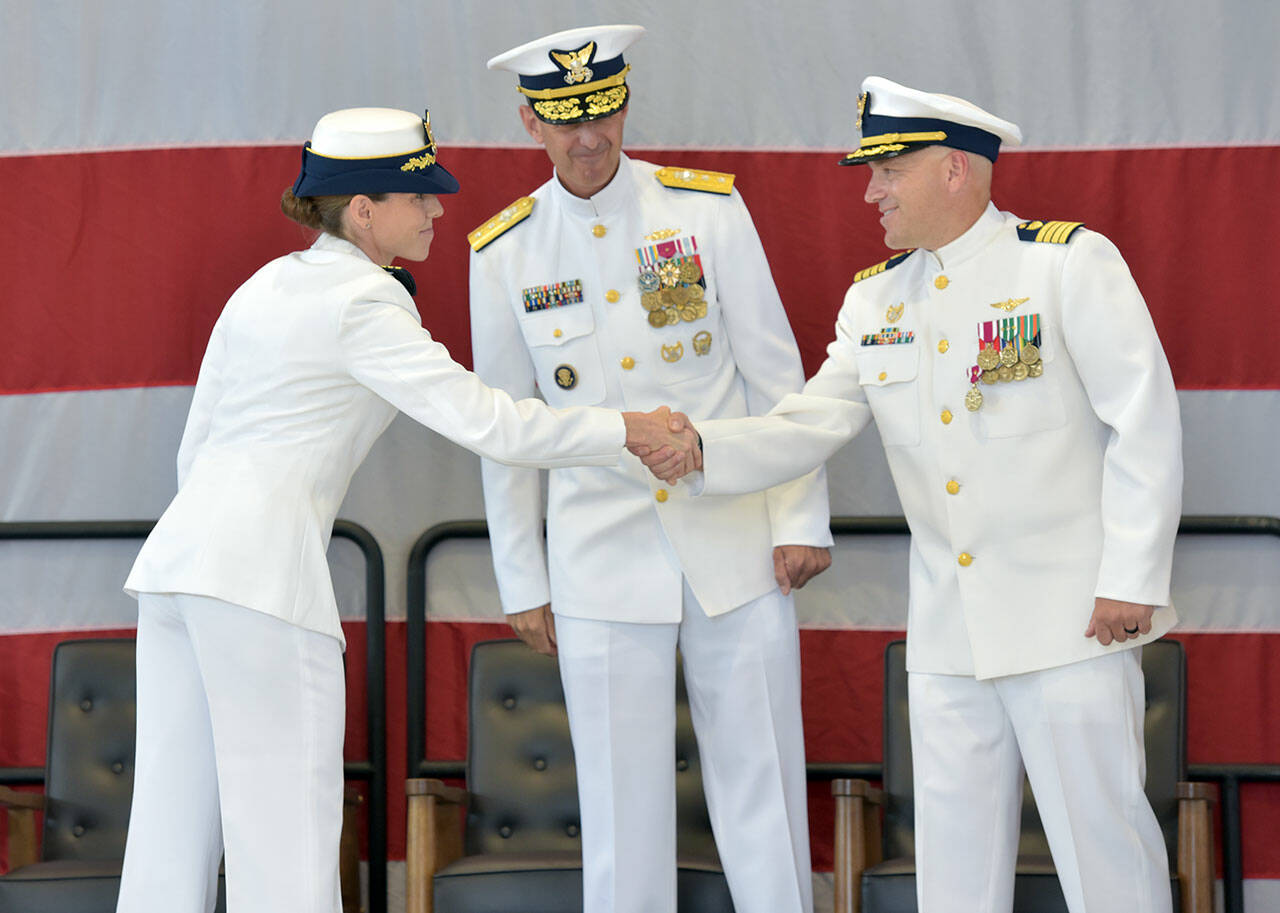 U.S. Coast Guard Cmdr. Kelly Higgins, left, shakes hands with outgoing Capt. Brent Schmadeke, right, as 13th District commander Rear Admiral Charles Fosse looks on during Friday’s change of command ceremony. Higgins will lead Air Station/Sector Field Office Port Angeles for two years after serving previously as executive officer and operations officer at Air Station San Francisco and Forward Operating Base Point Mugu, Calif. (Keith Thorpe/Peninsula Daily News)