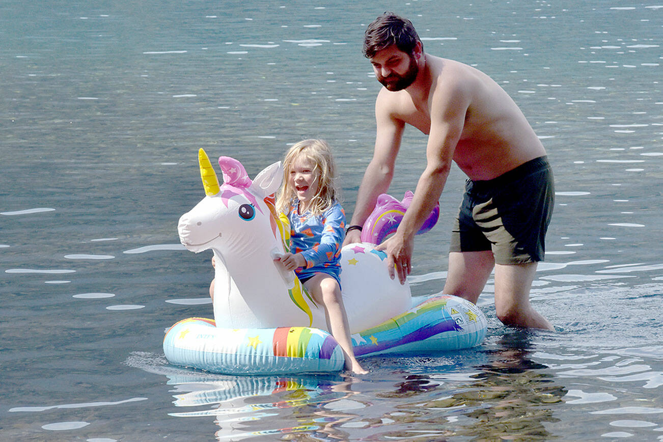 Maya Jennings-Kelly, 5, of Port Angeles gets a push from Nick Simpson of Port Angeles during an outing to Bovee’s Meadow at Lake Crescent in Olympic National Park on Saturday. Warm weekend weather drew hundreds of people to the Barnes Point area of the lake, leading to full parking lots and busy beaches. (Keith Thorpe/Peninsula Daily News)