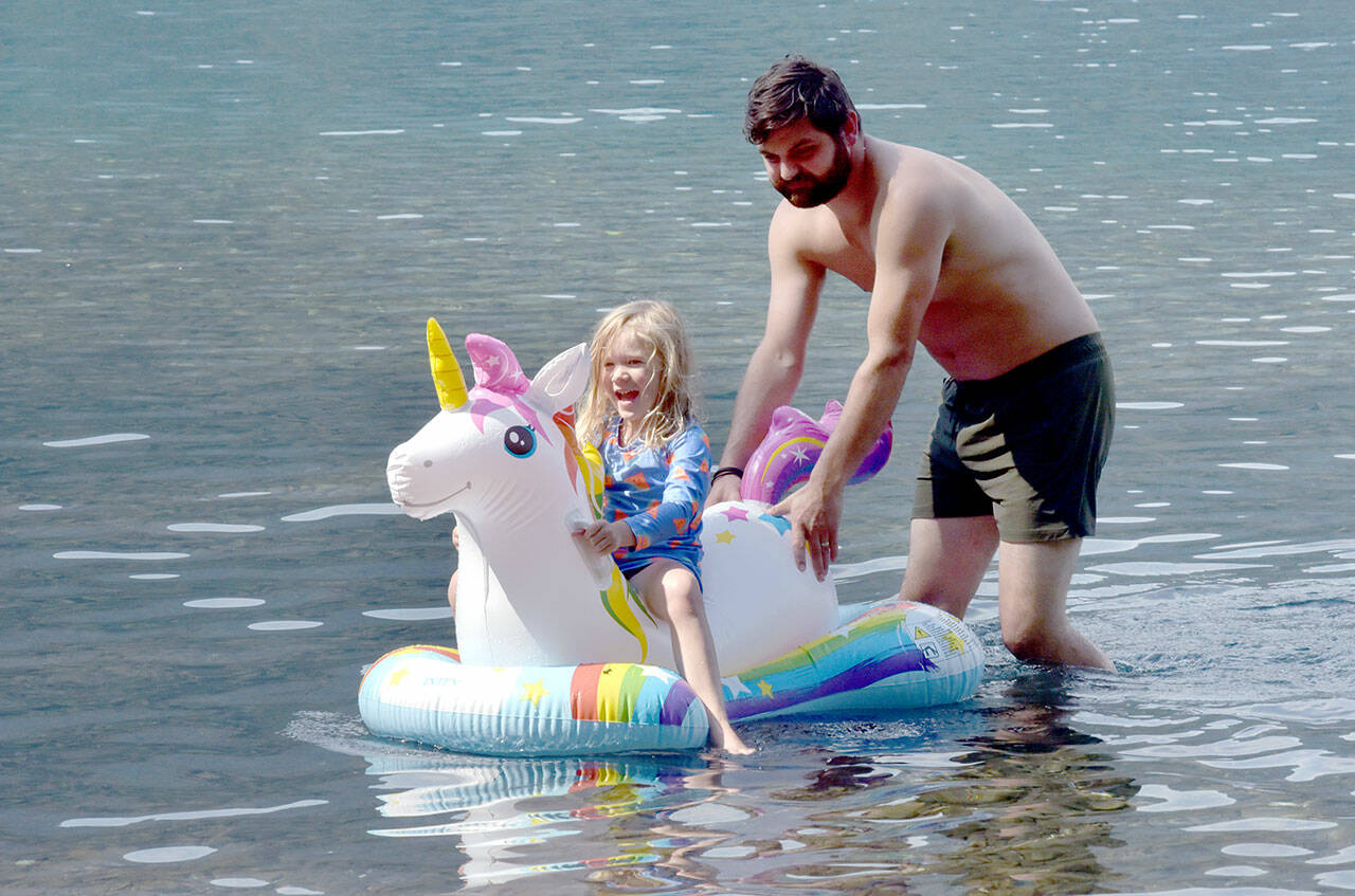 Maya Jennings-Kelly, 5, of Port Angeles gets a push from Nick Simpson of Port Angeles during an outing to Bovee’s Meadow at Lake Crescent in Olympic National Park on Saturday. Warm weekend weather drew hundreds of people to the Barnes Point area of the lake, leading to full parking lots and busy beaches. (Keith Thorpe/Peninsula Daily News)