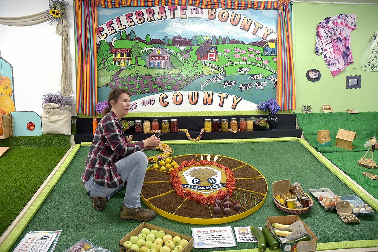 Erin Moilanen of the Crescent Grange arranges the group’s display in preparation for the Clallam County Fair on Tuesday in Port Angeles. (Keith Thorpe/Peninsula Daily News)