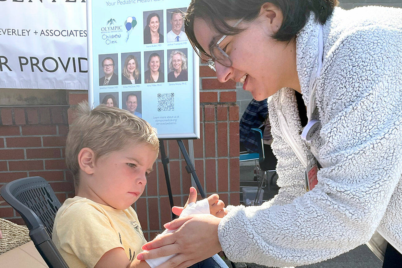 Atreyu Jones, 5, watches at Daisy Acedvado of Olympic Medica Center puts a fake cast on his arm at the Port Angeles School District’s 16th back to school fair for families and students on Saturday at Jefferson Elementary. Free haircuts, backpacks filled with school supplies and clothing were available for students, and health and community resource information was provided for parents. (Paula Hunt/Peninsula Daily News)