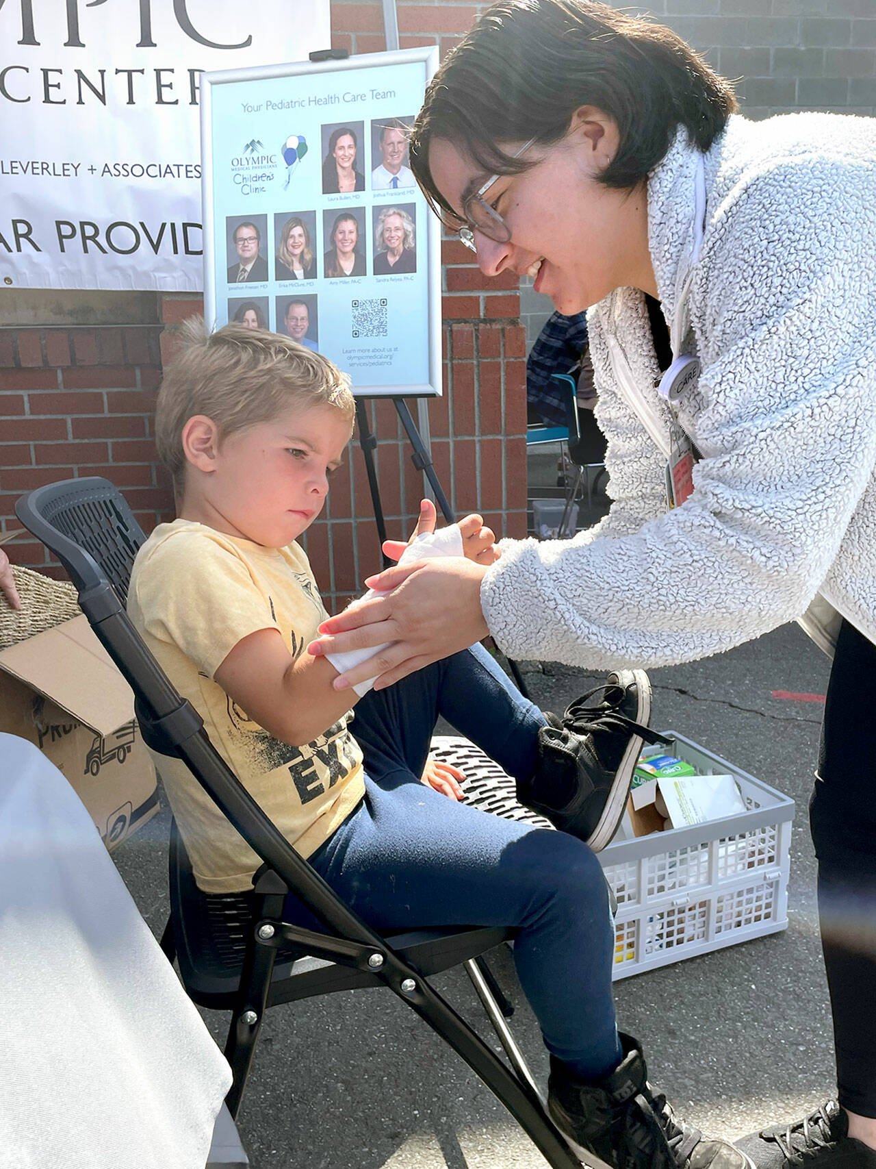 Atreyu Jones, 5, watches at Daisy Acedvado of Olympic Medica Center puts a fake cast on his arm at the Port Angeles School District’s 16th back to school fair for families and students on Saturday at Jefferson Elementary. Free haircuts, backpacks filled with school supplies and clothing were available for students, and health and community resource information was provided for parents. (Paula Hunt/Peninsula Daily News)