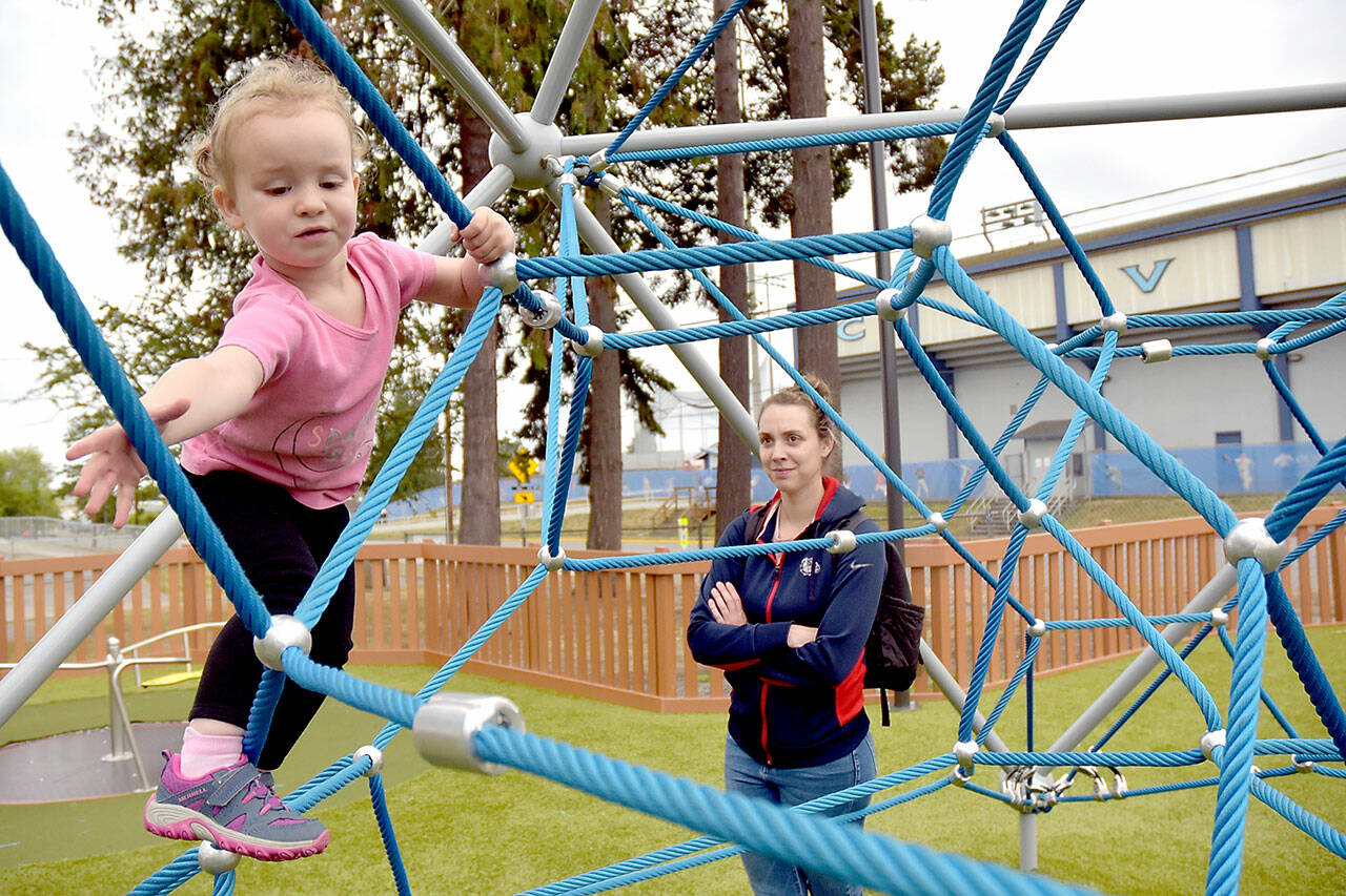 Nora Murray, 2, reaches for a handhold while climbing on a playground toy at the Dream Playground at Erickson Playfield as her mother, Christina Murray of Port Angeles, looks on. The pair were on a Wednesday outing to the popular Port Angeles playground. (Keith Thorpe/Peninsula Daily News)