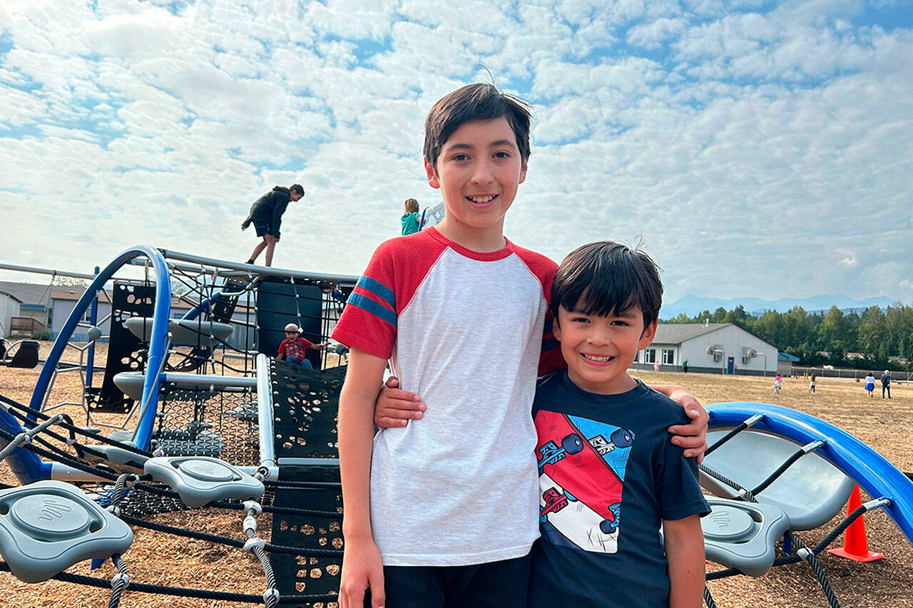 Ocean Mounts, 12, stands with his brother Ollie, 7, on Greywolf Elementary School’s new playground Quantis M2. Ocean suggested a new playground a few years ago, and Sequim School District and PTA leaders have sought funds for the project. He now attends Sequim Middle School and said he’s glad his brother and other children will get to play on the structure. (Matthew Nash/Olympic Peninsula News Group)