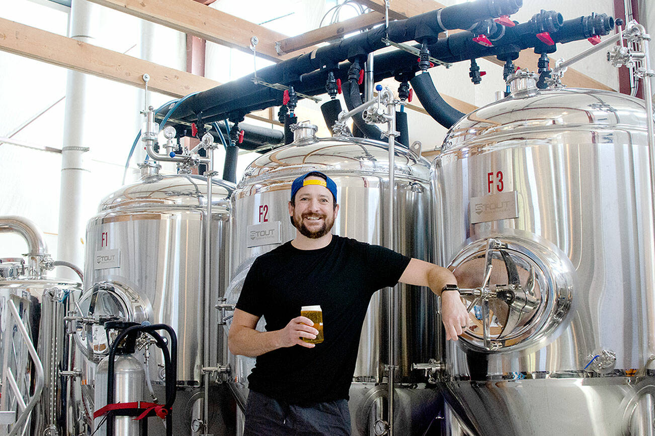 Levi Liberty enjoys one of his beers in front of Social Fabric Brewery’s three fermenters in Port Townsend. (Elijah Sussman/Peninsula Daily News)