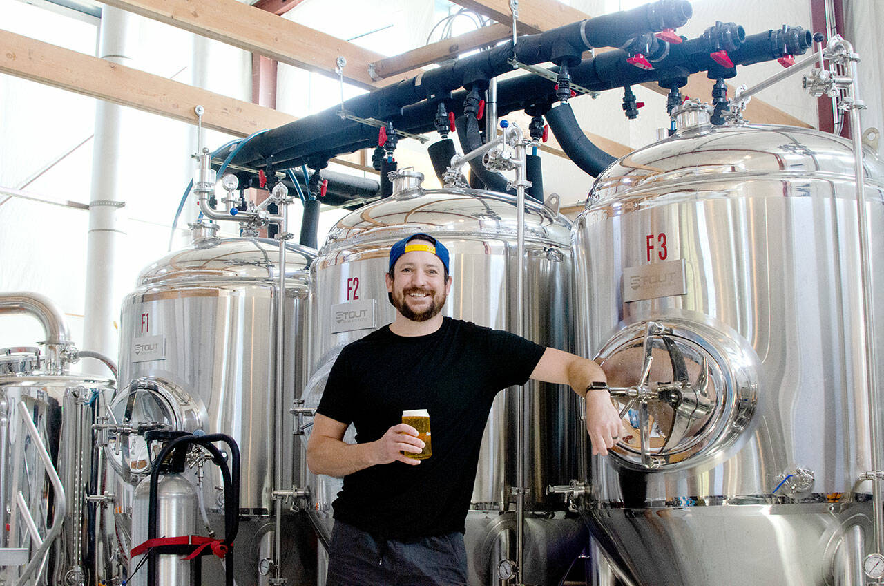 Levi Liberty enjoys one of his beers in front of Social Fabric Brewery’s three fermenters in Port Townsend. (Elijah Sussman/Peninsula Daily News)