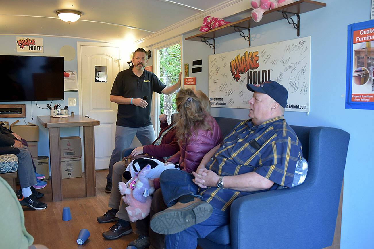 Tom Waertz of Ready America, left, runs an earthquake simulation in a shake trailer as participants, from left, Sequim EMT Lisa Law, CERT member Anne Koepp of Joyce and Jim Buck of the Joyce Emergency Planning and Preparation Group recover after being jolted by a 6.8-magnitude quake. (Keith Thorpe/Peninsula Daily News)