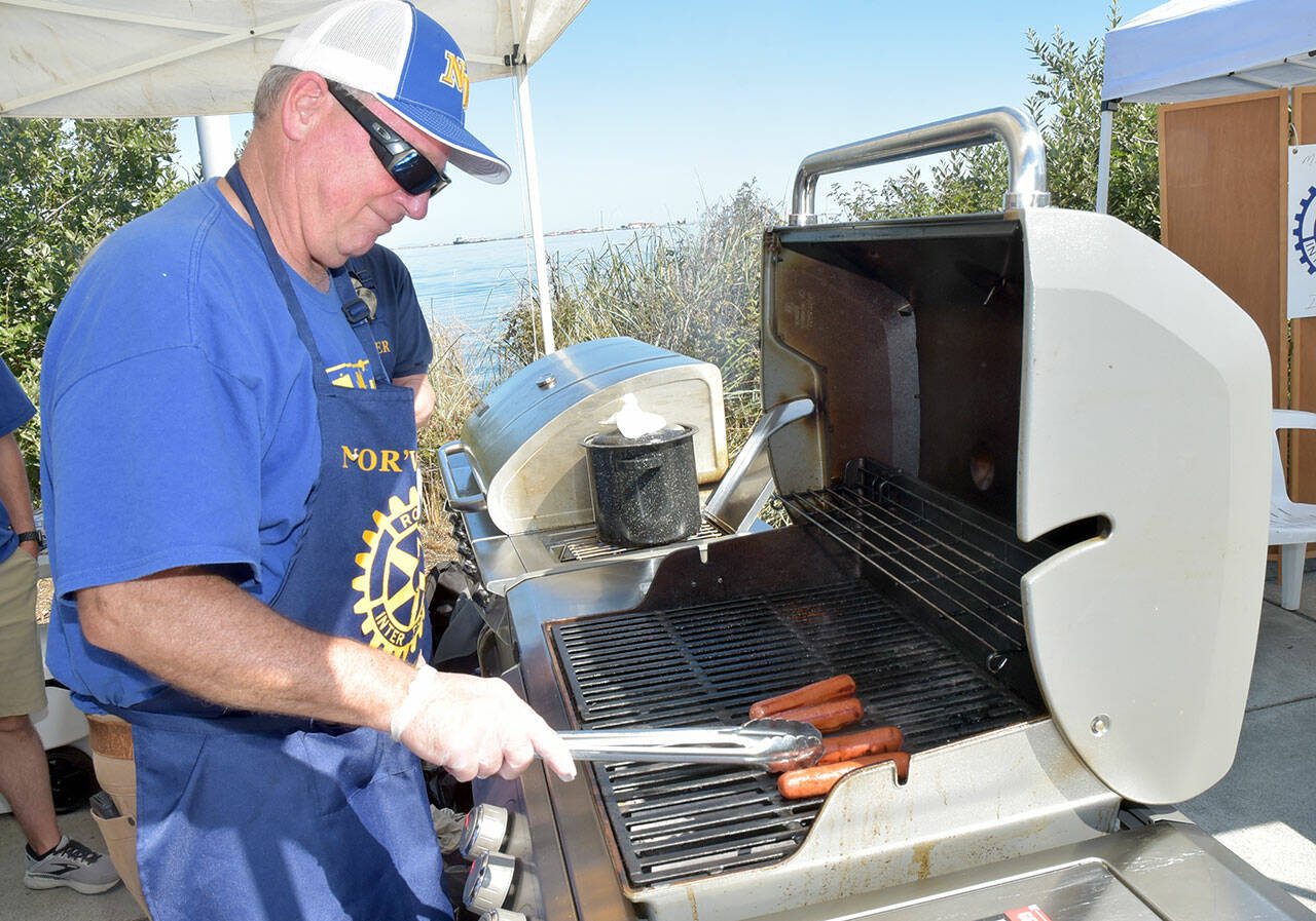 Nor’Wester Rotary member Chris Szczepczynski turns hot dogs for sale at Jammin’ in the Park on Saturday at Pebble Beach Park on the Port Angeles waterfront. (Keith Thorpe/Peninsula Daily News)