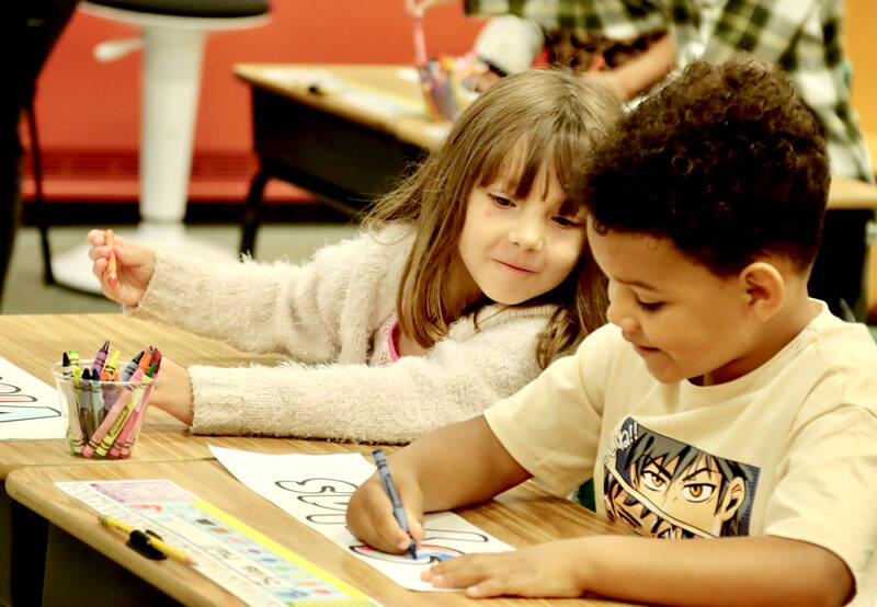 Violet Wilkie looks to see how her classmate Sylas Hall is coloring his name tag, the first chore on the first day of school Tuesday in Danika Johnson’s first-grade classroom at Hamilton Elementary in Port Angeles. (Dave Logan/for Peninsula Daily News)