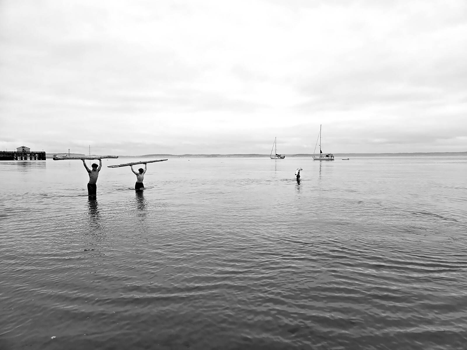 During an overhead static press lift and walk of a log, Port Townsend High School athletes Manaseh Lanphear Ramirez and Grady White both opted to challenge themselves above their knees, while Silas Klontz submerged himself beyond his armpits.