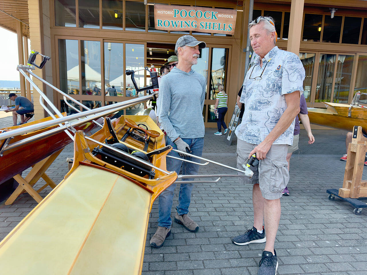 Steve Chapin, left, and Devin Dwyer discuss the finer points of Dwyer’s 1980 standard cedar Pocock-designed single scull. This scull and others are part of a display at the Wooden Boat Festival at Point Hudson Marina. (Steve Mullensky/ for Peninsula Daily News)