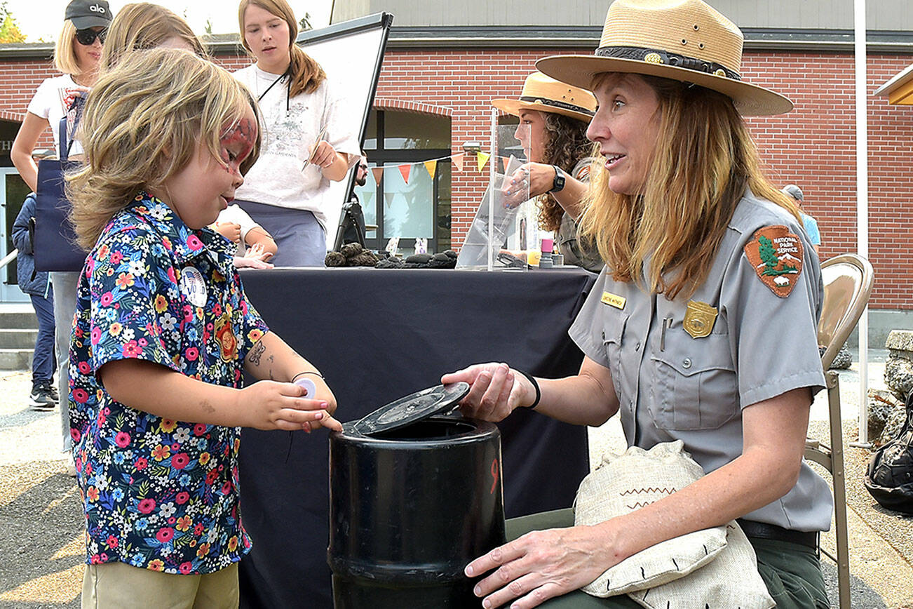 Ezra Rodriguez, 3, of Forks learns the workings of a bear canister with Olympic National Park Education Technician Christine Whitmarsh at the Peninsula College Fall Spectacular on Saturday in Port Angeles. (Keith Thorpe/Peninsula Daily News)