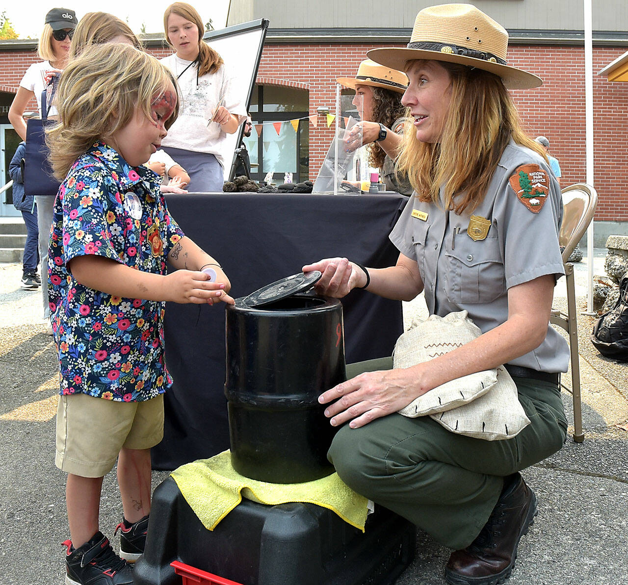 Ezra Rodriguez, 3, of Forks learns the workings of a bear canister with Olympic National Park Education Technician Christine Whitmarsh at the Peninsula College Fall Spectacular on Saturday in Port Angeles. (Keith Thorpe/Peninsula Daily News)