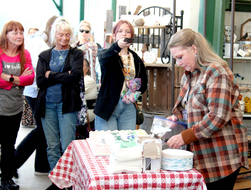 Kelly Grable of Mobile, Ala., prepares Bella’s birthday cake outside Forks Outfitters in Forks on Thursday as Forever Twilight in Forks fans look on. Isabella “Bella” Marie Cullen (née Swan) was born to Charlie Swan and Renée Dwyer on Sept. 13, 1987. The Twilight series’ main protagonist celebrated a day early as the store played along and paged her over the public address system. Grable is a member of the Forever Twilight Forks planning committee and travels to Forks each year to help with the festival. More than 400 VIT (Very Important Twilighter) tickets were sold. Planned VIT and other free activities continue throughout town and to La Push through Sunday. (Christi Baron/Olympic Peninsula News Group)