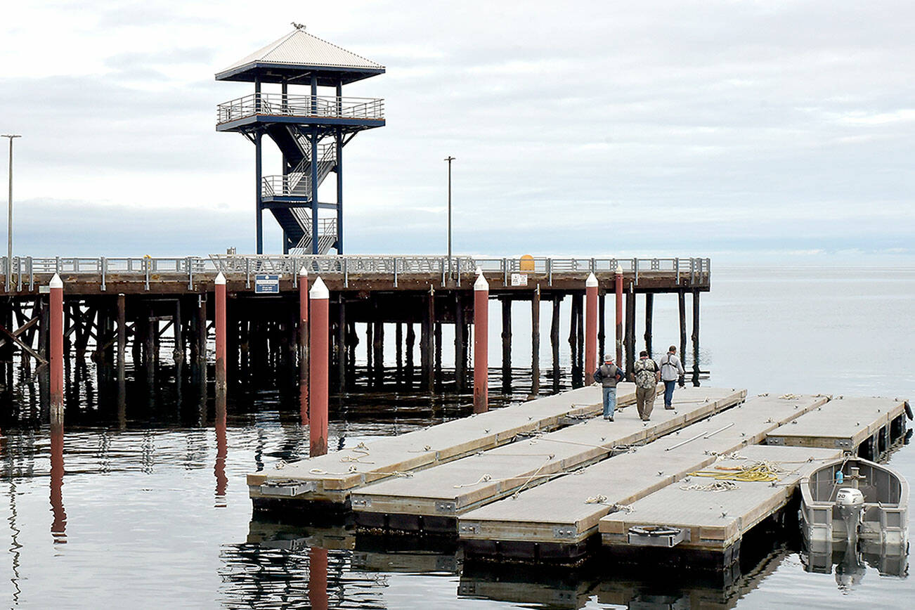 Port Angeles Parks Department workers walk along the Port Angeles City Pier moorage floats after they were removed for seasonal storage on Tuesday. The floats will be towed to a storage area near the McKinley Paper mill to protect them from winter winds and waves. (Keith Thorpe/Peninsula Daily News)