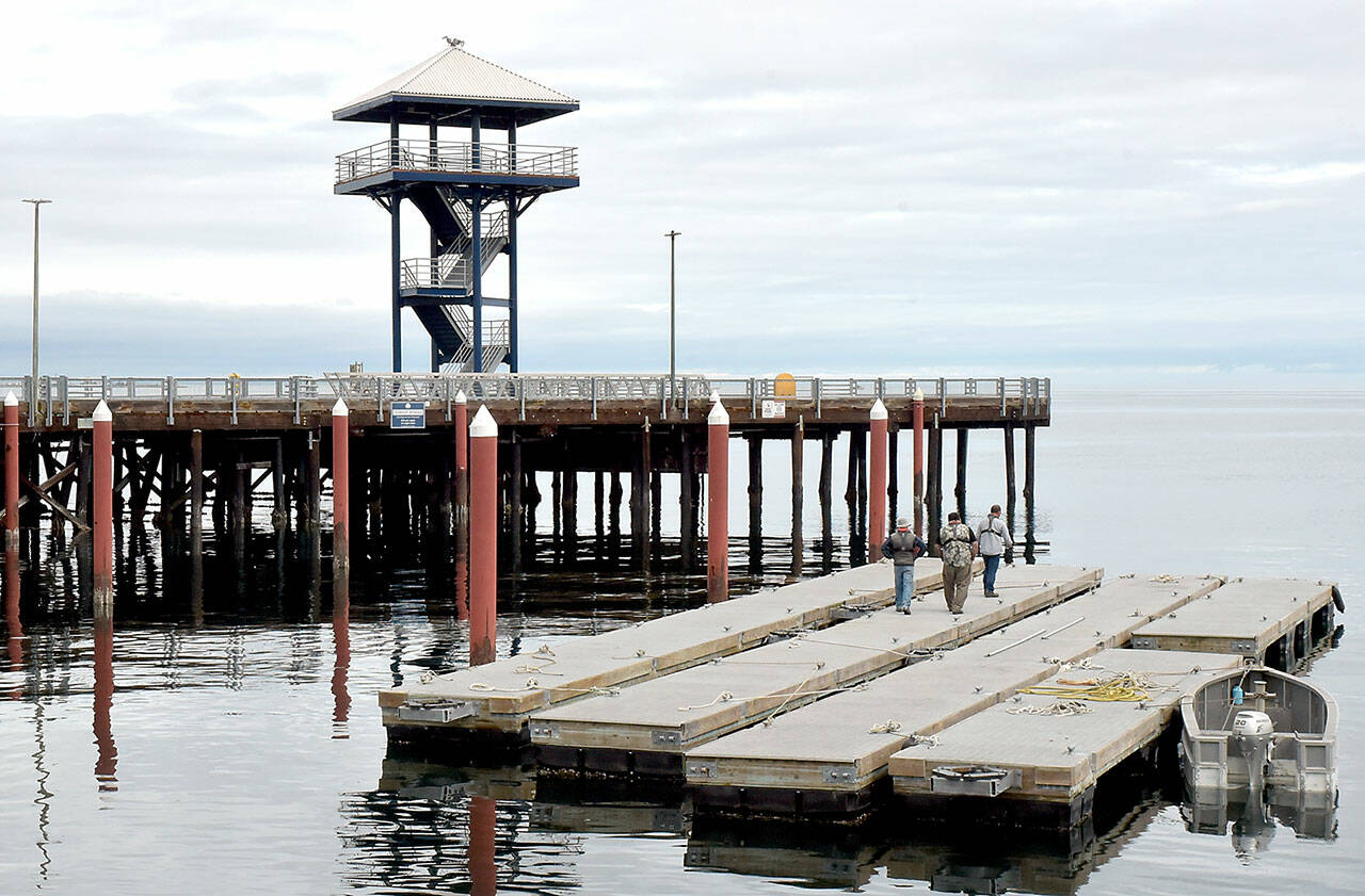 Port Angeles Parks Department workers walk along the Port Angeles City Pier moorage floats after they were removed for seasonal storage on Tuesday. The floats will be towed to a storage area near the McKinley Paper mill to protect them from winter winds and waves. (Keith Thorpe/Peninsula Daily News)