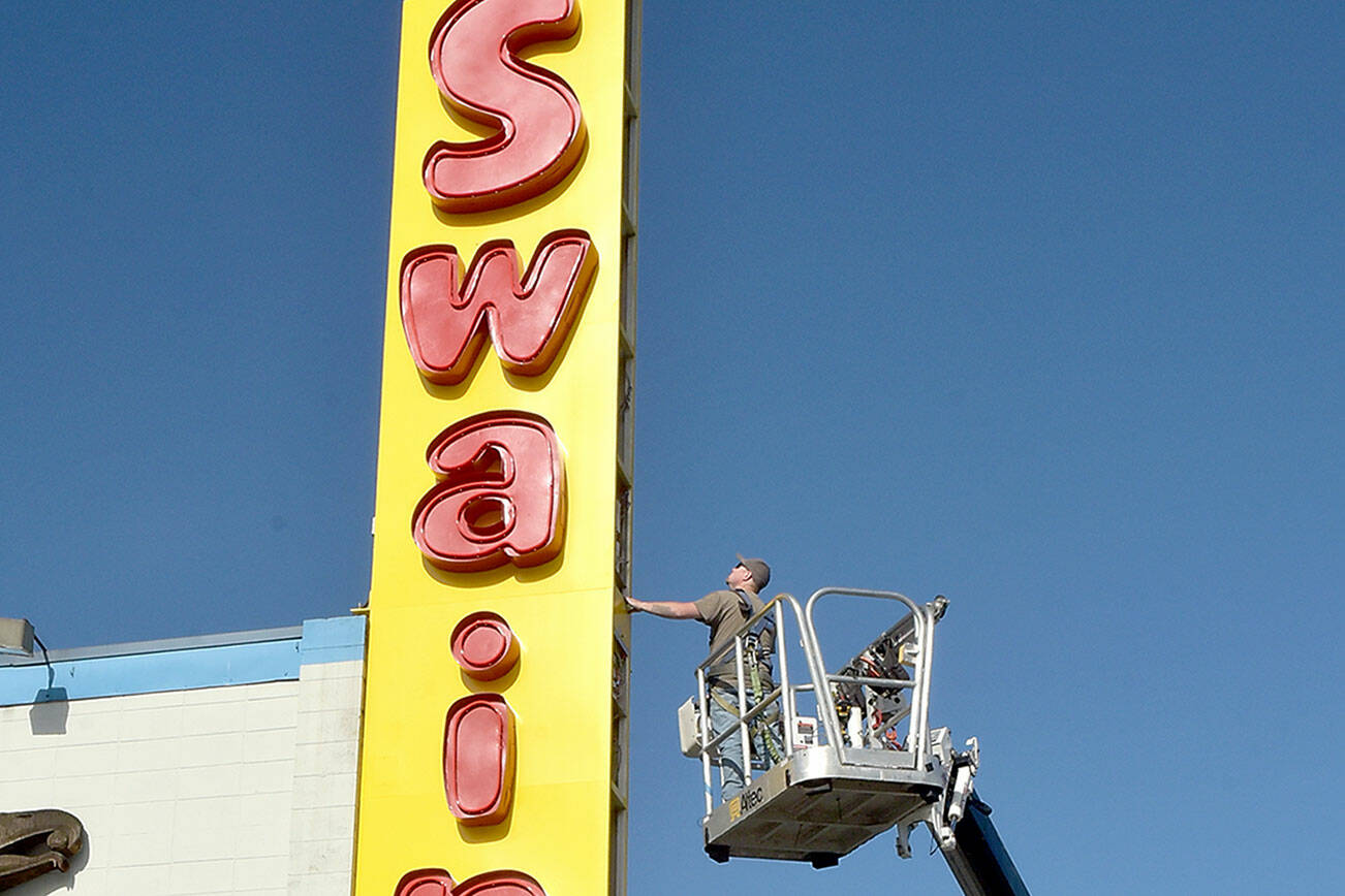 Seth Stewart of Silverdale-based Hanson Signs inspects the side panels on a new business sign at Swain’s General Store in Port Angeles on Thursday. Swain’s general manager Don Droz said the original iconic sign dated back to the 1960s and was in need being replaced. Droz said the neon-lit lettering from the old sign was preserved and incorporated into the new marquee. (Keith Thorpe/Peninsula Daily News)