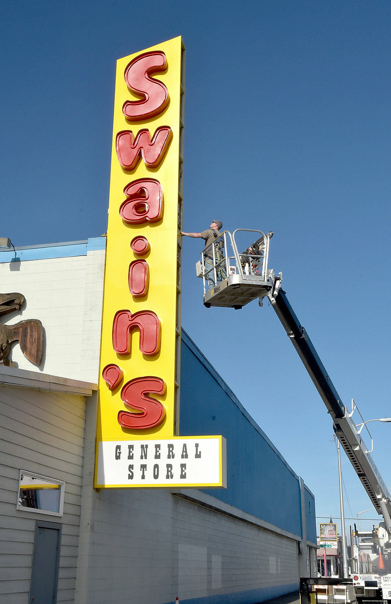 Seth Stewart of Silverdale-based Hanson Signs inspects the side panels on a new business sign at Swain’s General Store in Port Angeles on Thursday. Swain’s general manager Don Droz said the original iconic sign dated back to the 1960s and was in need being replaced. Droz said the neon-lit lettering from the old sign was preserved and incorporated into the new marquee. (Keith Thorpe/Peninsula Daily News)