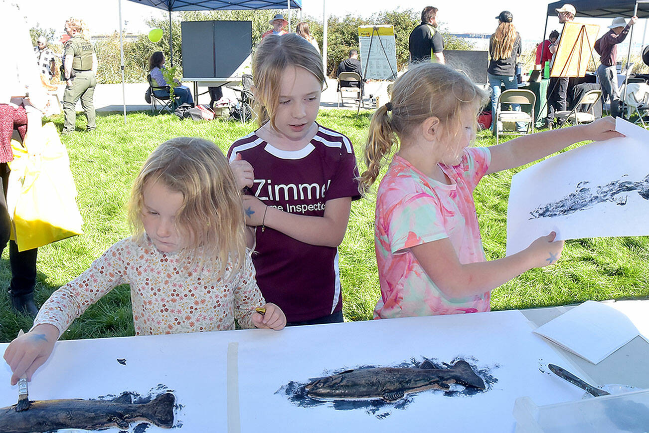 Port Angeles siblings, from left, Parker Ahlgrim, 4, Mckenna Ahlgrim, 8, and Sierra Ahlgrim, 6, make fish prints at a booth set up by the Port Angeles Fine Arts Center during Saturday’s Forever StreamFest at Pebble Beach Park on the Port Angeles waterfront. The event, hosted by the Port Angeles Garden Club in conjunction with the Clallam County Conservation District, featured a variety of information booths and activities focused on protecting the environment and natural resources. (Keith Thorpe/Peninsula Daily News)