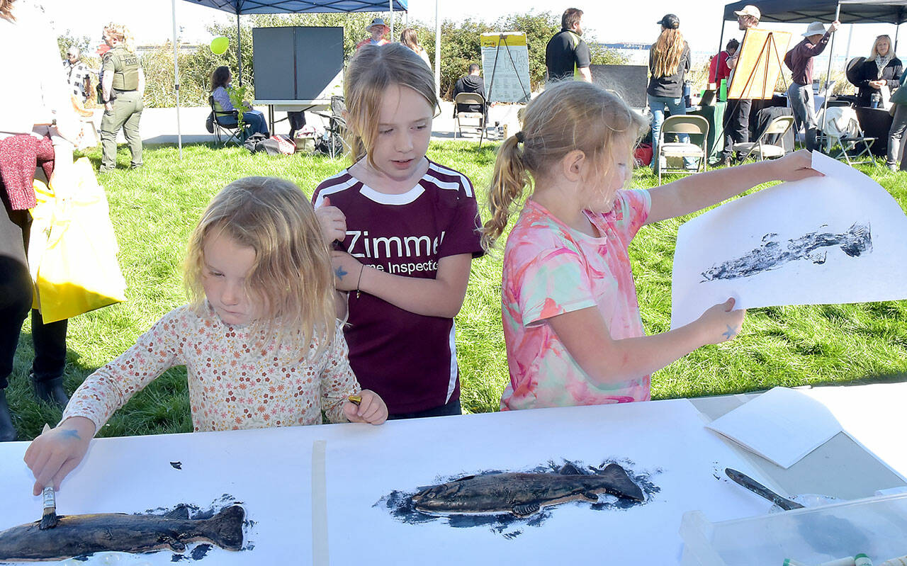 Port Angeles siblings, from left, Parker Ahlgrim, 4, Mckenna Ahlgrim, 8, and Sierra Ahlgrim, 6, make fish prints at a booth set up by the Port Angeles Fine Arts Center during Saturday’s Forever StreamFest at Pebble Beach Park on the Port Angeles waterfront. The event, hosted by the Port Angeles Garden Club in conjunction with the Clallam County Conservation District, featured a variety of information booths and activities focused on protecting the environment and natural resources. (Keith Thorpe/Peninsula Daily News)