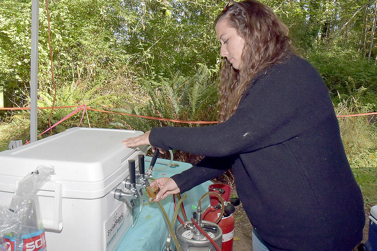 Moya Cavanagh, a teacher with Olympic Nature Experience, pours a taster glass with beer during Saturday’s Beer in the Woods at Webster’s Woods at the Port Angeles Fine Arts Center. The event featured food, music, youth activities and samples of various breweries around Northwest Washington. (Keith Thorpe/Peninsula Daily News)