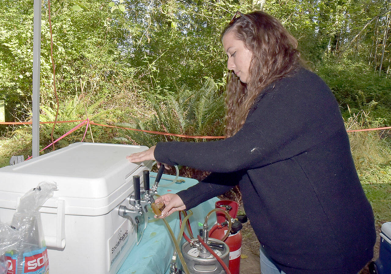 Moya Cavanagh, a teacher with Olympic Nature Experience, pours a taster glass with beer during Saturday’s Beer in the Woods at Webster’s Woods at the Port Angeles Fine Arts Center. The event featured food, music, youth activities and samples of various breweries around Northwest Washington. (Keith Thorpe/Peninsula Daily News)