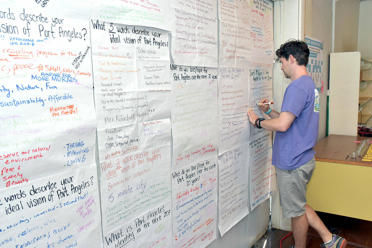 Greg Maust of Port Angeles adds his suggestions to a wall devoted to visions and suggestions for the city’s future during a Storefront Studio open house on Tuesday hosted by the city at 230 E. First St. The studio, staffed by city planners, continues today with displays and a workshop. (Keith Thorpe/Peninsula Daily News)