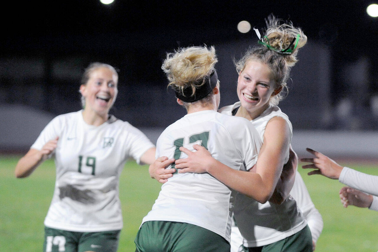 Port Angeles’ Lilly Anne Lancaster, right, hugs teammate Ava-Anne Sheahan after scoring the game-winning goal in double overtime in the Riders’ 3-2 win over rival Sequim on Thursday. (Michael Dashiell/Olympic Peninsula News Group)