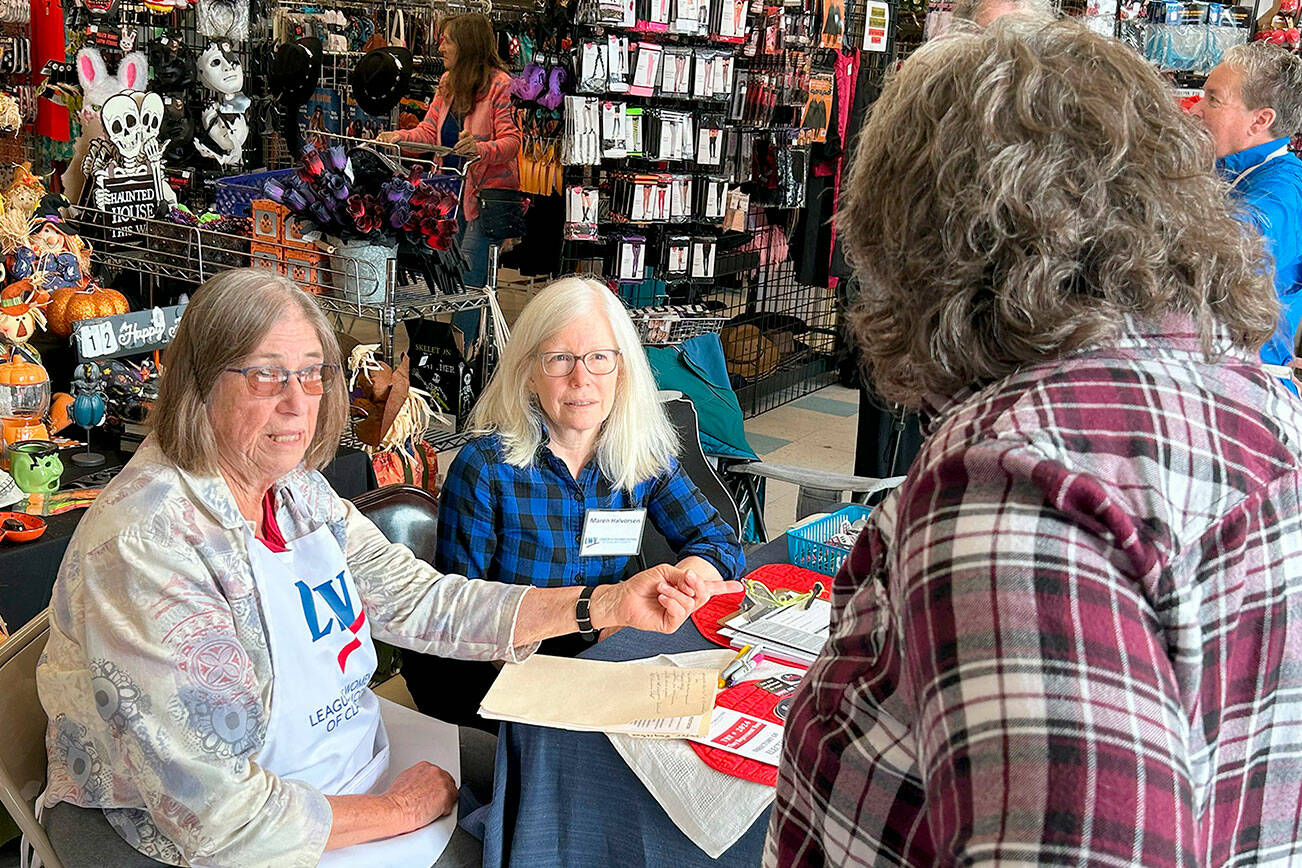 Volunteers Barbara VanderWerf and Maren Halverson, with the League of Women Voters of Clallam County, speak with a customer at Sequim Goodwill about ballot information on Sept. 17 during an information session held in conjunction with the stores in Sequim and Port Angeles on National Voter Registration Day. (Matthew Nash/Olympic Peninsula News Group)