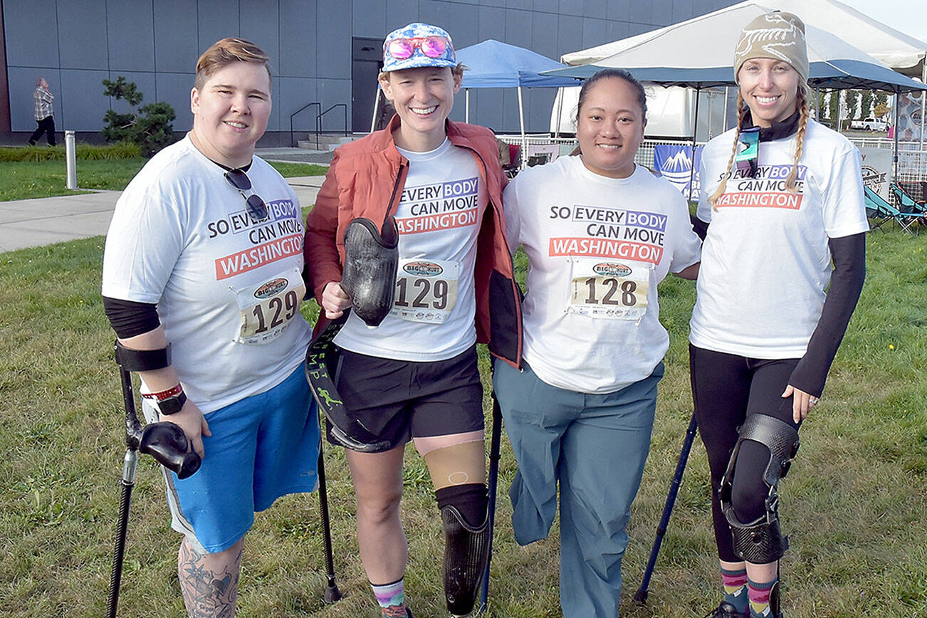 Members of the “So Every BODY Can Move” teams competing at the Big Hurt get await their mountain bike teammates Saturday at Pebble Beach in Port Angeles. From left are Katya Madden (kayak), Nicole Ver Kuilen (cycling, running), Sierra Landholm (kayak) and Katy Gaastra (cycling). The group is working to require insurance companies to help pay for orthotics and prosthetics so people can not only be mobile but to be able to run and cycle. (Keith Thorpe/Peninsula Daily News)