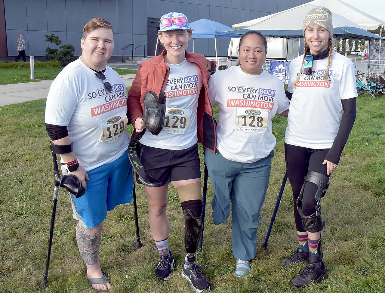 Members of the “So Every BODY Can Move” teams competing at the Big Hurt get await their mountain bike teammates Saturday at Pebble Beach in Port Angeles. From left are Katya Madden (kayak), Nicole Ver Kuilen (cycling, running), Sierra Landholm (kayak) and Katy Gaastra (cycling). The group is working to require insurance companies to help pay for orthotics and prosthetics so people can not only be mobile but to be able to run and cycle. (Keith Thorpe/Peninsula Daily News)