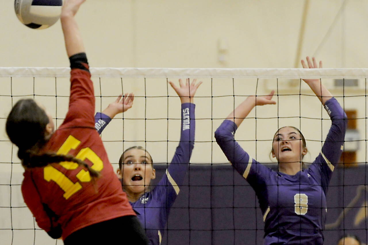 Sequim's Sydney Clark, left, and Rose Gibson rise up to block a kill attempt from Kingston's Maddie Brown (15). Sequim won 3-0 to remain near the top of the Olympic League standings. (Michael Dashiell/for Peninsula Daily News)