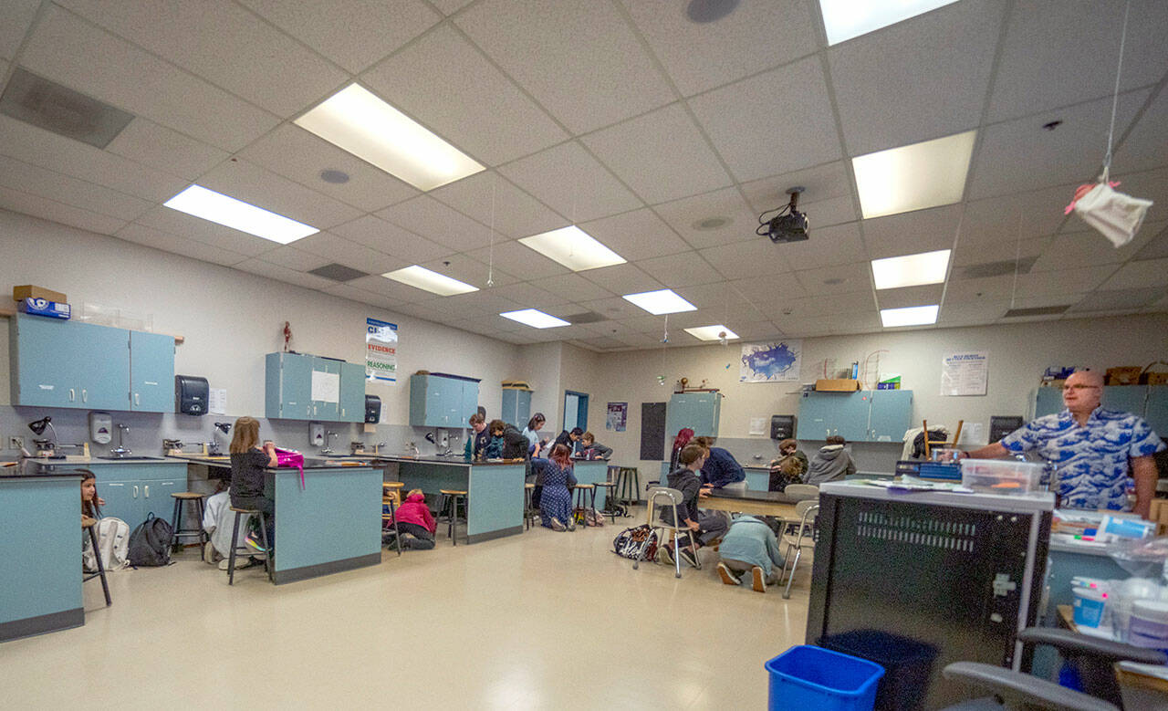 Students in Niall Twomey’s seventh-grade science class take cover under their workstations during a Great Shakeout drill on Thursday at Blue Heron Middle School in Port Townsend. The students dropped, took cover and held on for the duration of the 30-second drill in order to build muscle memory in the event of a real earthquake or tsunami on the Peninsula. (Steve Mullensky/for Peninsula Daily News)