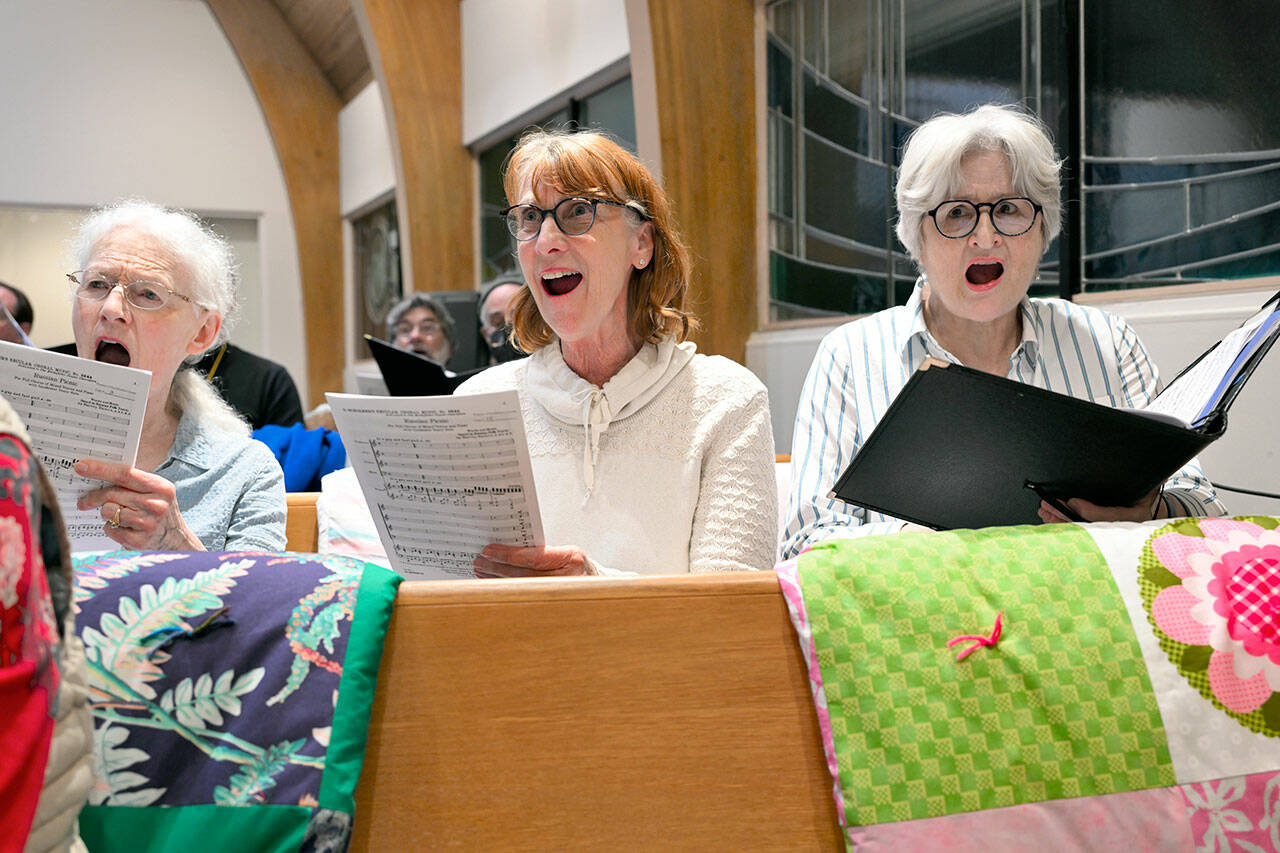 RainShadow Chorale singers Linda Bach, Lisa Hoffman and Jane Hutcheson, all of Port Townsend, rehearse for “All Night VIgil.” (Karl Perry/RainShadow Chorale)