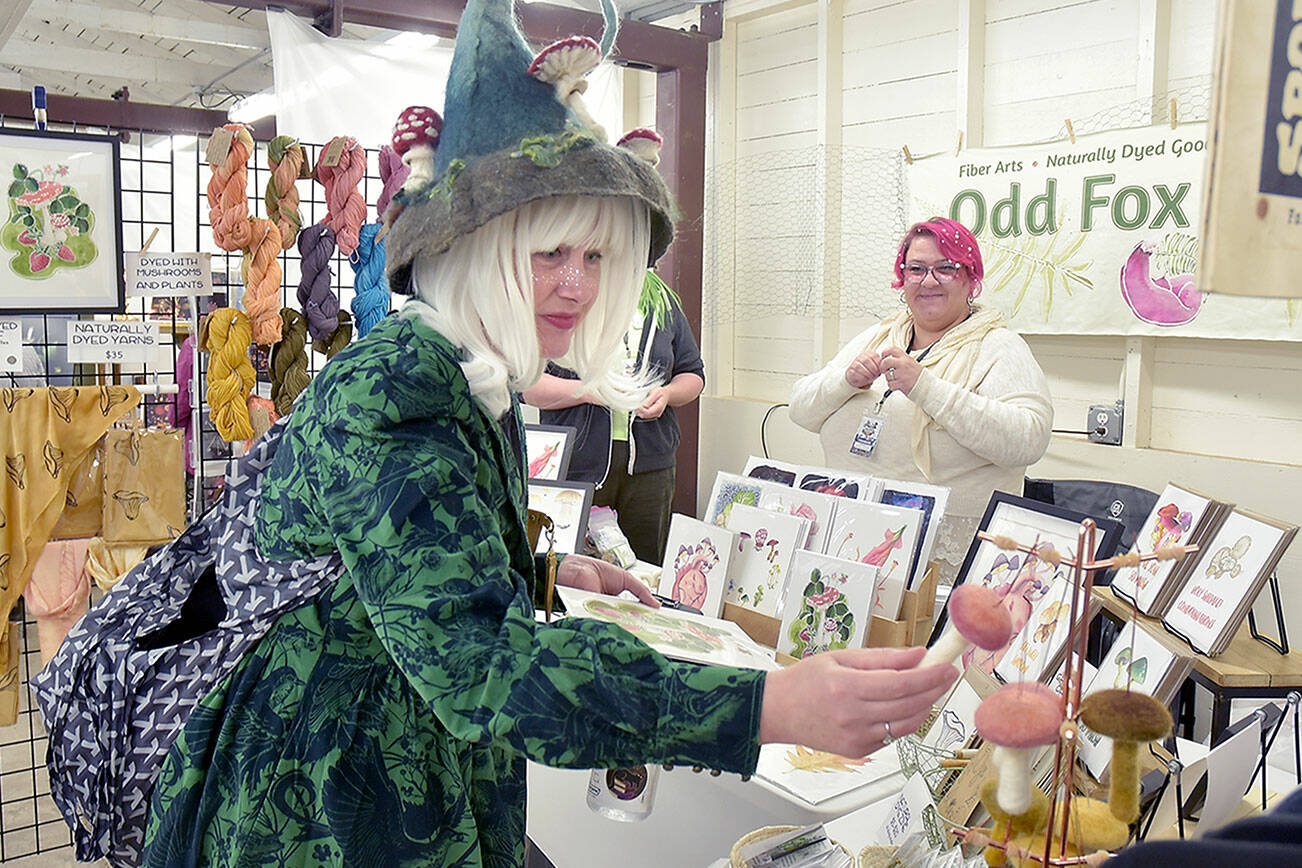 Karyn Bocko of Port Angeles, front, looks at mushroom merchandise at the annual Fungi Festival on Saturday at the Clallam County Fairgrounds. Looking on at right is Freya Gereke of Portland-based Odd Fox & Fern. The two-day event brought together mushroom fans for a weekend of fungus appreciation, along with food, merchandise and workshops. (Keith Thorpe/Peninsula Daily News)