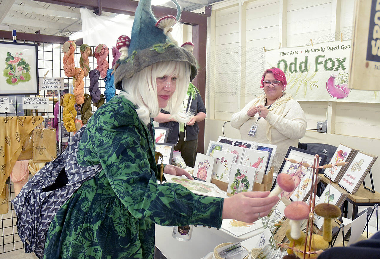 Karyn Bocko of Port Angeles, front, looks at mushroom merchandise at the annual Fungi Festival on Saturday at the Clallam County Fairgrounds. Looking on at right is Freya Gereke of Portland-based Odd Fox & Fern. The two-day event brought together mushroom fans for a weekend of fungus appreciation, along with food, merchandise and workshops. (Keith Thorpe/Peninsula Daily News)