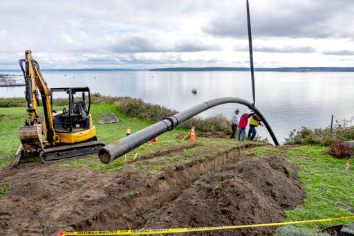 Workers guide a new 125-foot-long, 1,500-pound section of stormwater drain pipe into a trench above the Larry Scott Trail on Tuesday in Port Townsend. The new pipe is bigger and made from a different material than the PVC that it replaced. Last winter, the old pipe fractured in places due to weather and caused dirt and rocks to slide onto the trail. (Steve Mullensky/for Peninsula Daily News)