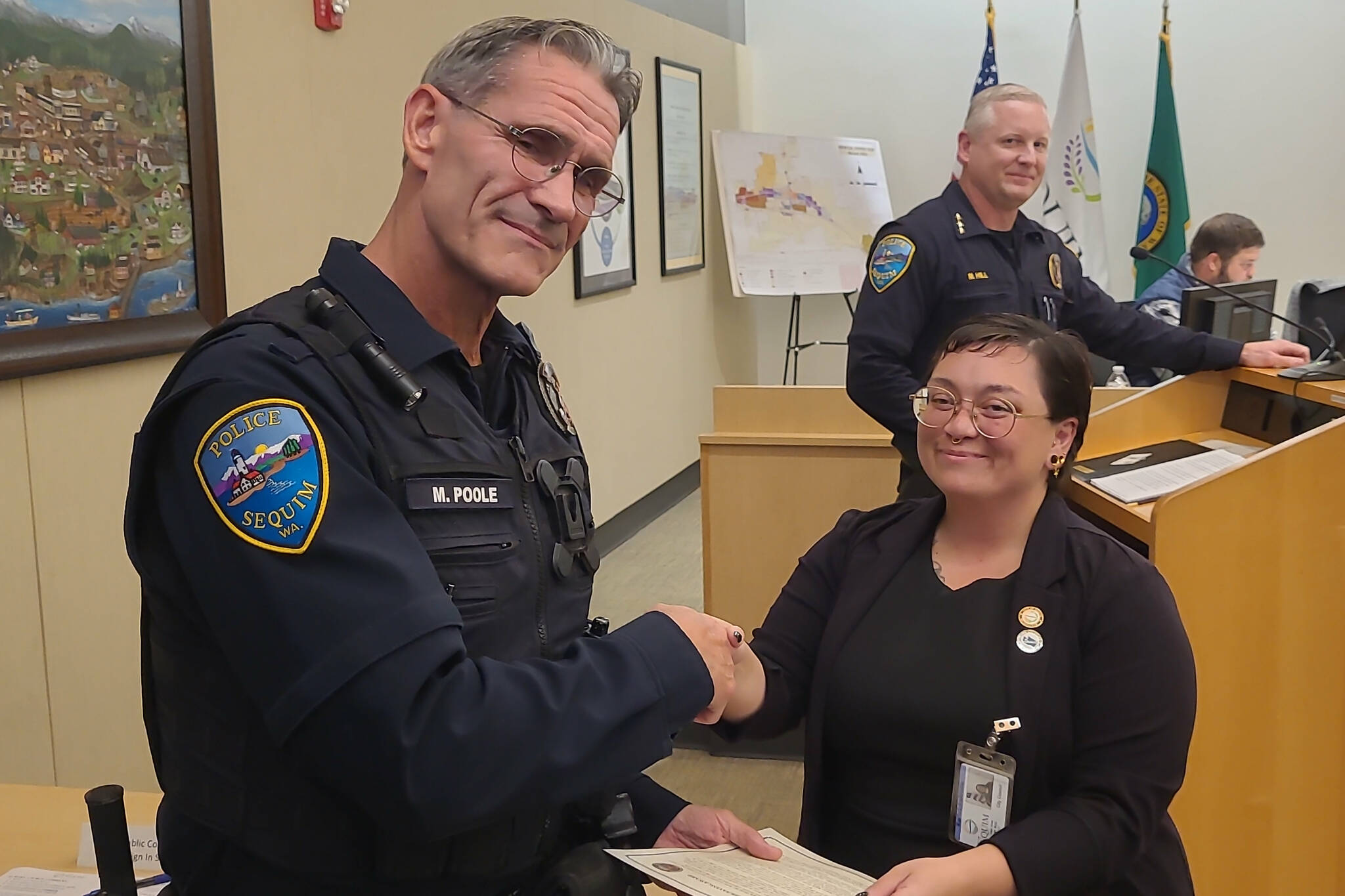 Deputy Mayor Rachel Anderson thanks Sequim police officer Mark Poole with a proclamation of his Lifesaving Award on Oct. 14 for preventing a man from jumping from the River Road bypass in August. (John Southard)